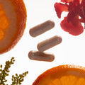 Supplements with oranges and flowers on a white background