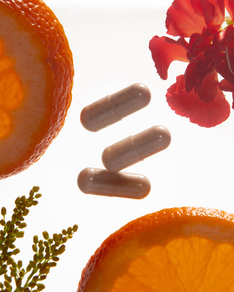 Supplements with oranges and flowers on a white background